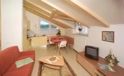 a living room with a red couch and a kitchen at Roter Adler in Caldaro