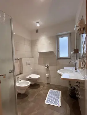 a bathroom with two sinks and a toilet and a window at Roter Adler in Caldaro