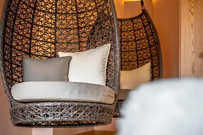a wicker chair with pillows in a room at Dolomitenhotel Weisslahnbad in Tires