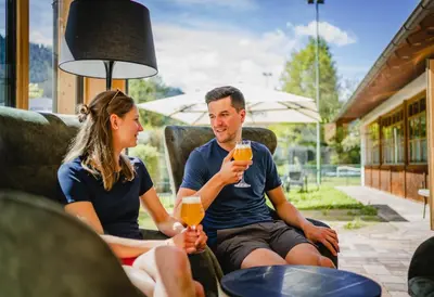 a man and woman sitting on a patio drinking orange juice at Dolomitenhotel Weisslahnbad in Tires