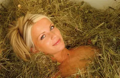 a woman laying on the ground in some hay at Dolomitenhotel Weisslahnbad in Tires