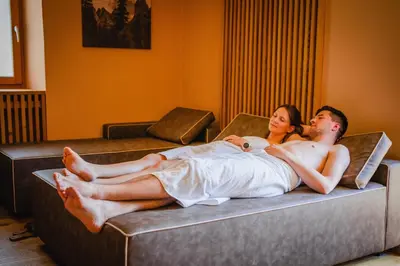 a man and a woman laying on a bed at Dolomitenhotel Weisslahnbad in Tires