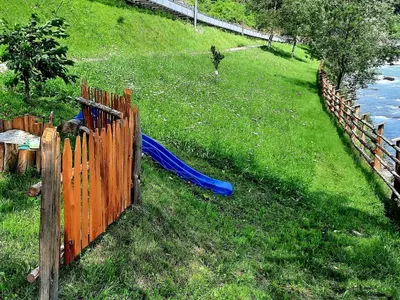 a wooden fence with a blue hose in the grass at Chalet Passeier - RIVER in Saltusio