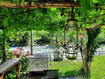 a glass lamp hanging from a pergola in a garden at Chalet Passeier - RIVER in Saltusio