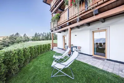 a pair of white chairs sitting on a lawn at Gfliererhof in Fiè
