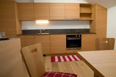 a kitchen with wooden cabinets and a table with a sink at Wegmacherhof in Castelrotto