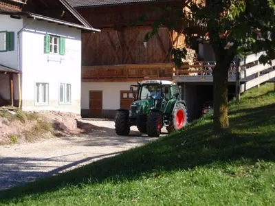 a green tractor parked next to a house at Wegmacherhof in Castelrotto