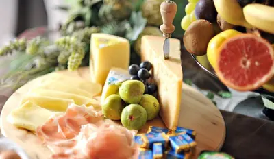 a cutting board with different types of cheese and fruit at Hotel Monte Civetta in Alleghe