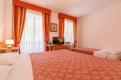 a hotel room with two beds and a television at Hotel Monte Civetta in Alleghe