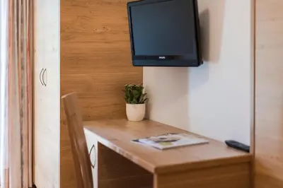 a television on a wall above a wooden table at Petaunerhof in Schenna