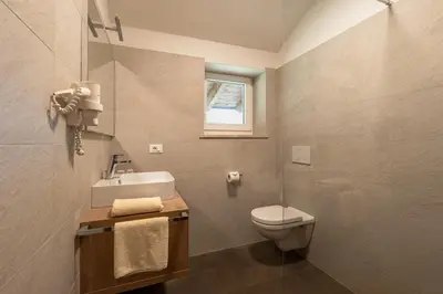 a bathroom with a toilet and a sink and a window at Petaunerhof in Schenna