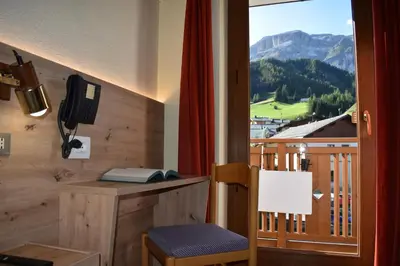 a room with a desk and a balcony with a phone at Albergo Pensione Sport in Arabba