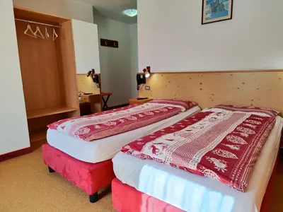 two beds in a hotel room with red and white blankets at Albergo Pensione Sport in Arabba