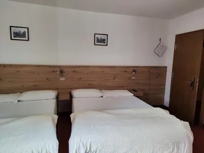 two beds in a room with white sheets at Albergo Pensione Sport in Arabba