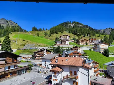 a village in the mountains with a green hill at Albergo Pensione Sport in Arabba