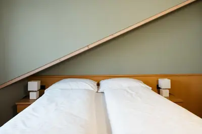 two beds with white sheets and two lights on them at Residence Isarcus in Bressanone
