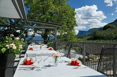 a table with wine glasses and flowers on a balcony at Gasthof Falger in Vollan