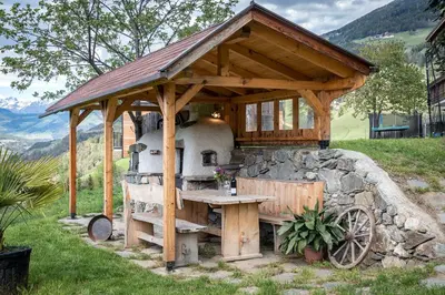 a outdoor oven with a table and a stone wall at Linderhof in Bressanone