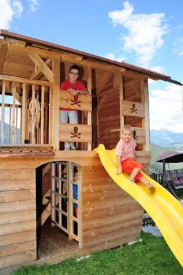 a man and a child sitting on a slide in a play house at Linderhof in Bressanone