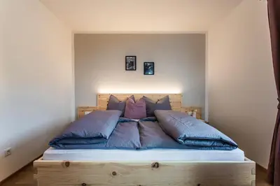 a bed with blue pillows on it in a room at Haidgerberhof - apartments & homemade food in Longomoso