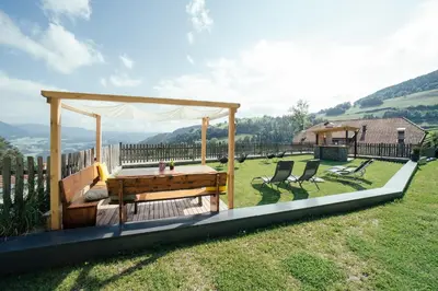 a wooden gazebo with a table and two chairs at Haidgerberhof - apartments & homemade food in Longomoso