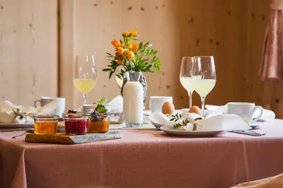 a table with glasses of wine and flowers on it at Haidgerberhof - apartments & homemade food in Longomoso