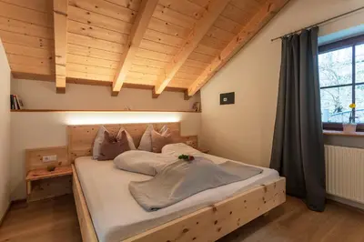 a bedroom with a large bed with a wooden headboard at Haidgerberhof - apartments & homemade food in Longomoso