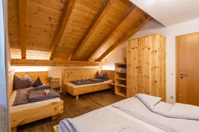 a bedroom with two beds and wooden ceilings at Haidgerberhof - apartments & homemade food in Longomoso