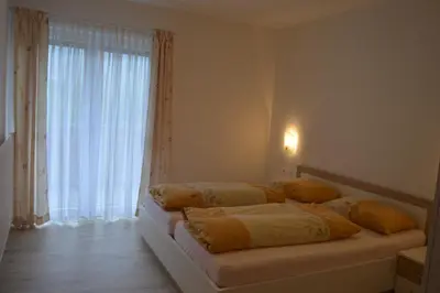 a bedroom with two beds and a large window at Vermietung Obermais in Merano