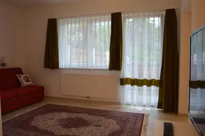 a living room with a red couch and two windows at Vermietung Obermais in Merano