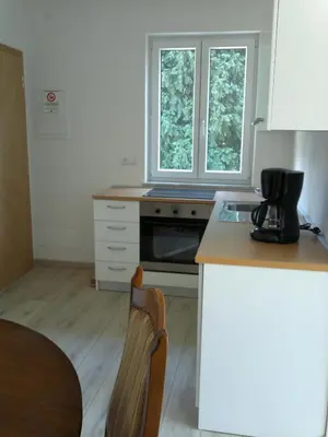 a kitchen with a counter and a stove and two windows at Vermietung Obermais in Merano