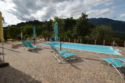 a swimming pool with blue chairs and umbrellas at Vermietung Obermais in Merano