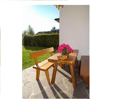 a wooden table with a chair and flowers on it at Appartments Geislerblick in Castelrotto