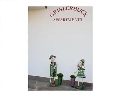 a couple of dolls standing in front of a building at Appartments Geislerblick in Castelrotto