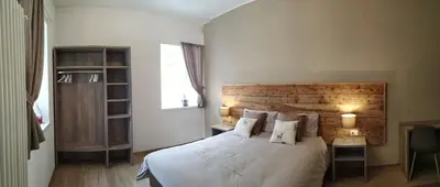 a bedroom with a bed with white sheets and pillows at Le Bifore in valle in Predazzo