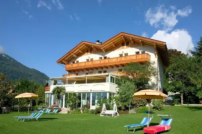 a building with chairs and umbrellas in front of it at Hotel Öhlerhof in Lagundo