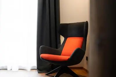 a black and orange chair sitting next to a window at Chalet Insignis in Santa Cristina in Val Gardena