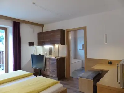 a room with two beds and a television and a bathroom at Ferienwohnungen Braiter in Rifiano