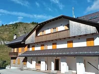 a white building with a black roof at LA PULCE INNEVATA - mansarda sulle piste, Dolomiti Affitti in Passo Rolle