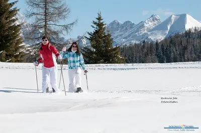 two women are standing on skis in the snow at Suite Cima Pape in Rocca Pietore