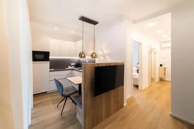 a kitchen and living room with a television and a dining table at Meranosuites - Garden in Merano