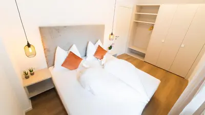 a white bed with pillows on it in a room at Meranosuites - Garden in Merano