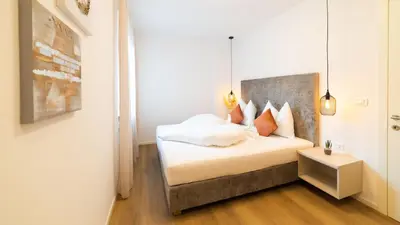 a bedroom with a bed with a headboard and a table at Meranosuites - Garden in Merano