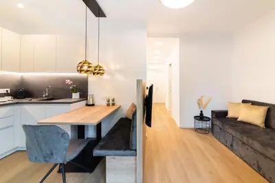 a kitchen and living room with a table and a couch at Meranosuites - Garden in Merano