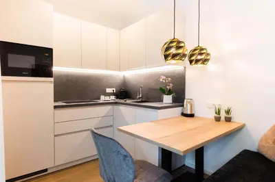 a kitchen with white cabinets and a wooden table at Meranosuites - Garden in Merano