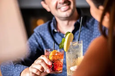a man and a woman holding two cocktails at Berghotel Jochgrimm - Your Dolomites Home in Varena