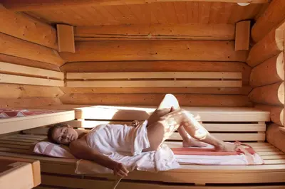 a woman laying in a wooden sauna at Berghotel Jochgrimm - Your Dolomites Home in Varena