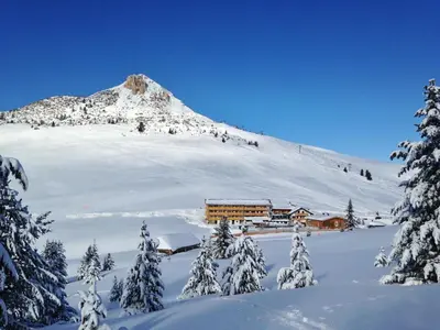 a snow covered mountain with a building in the foreground at Berghotel Jochgrimm - Your Dolomites Home in Varena
