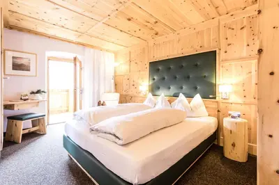 a bedroom with a large bed with a wooden ceiling at Berghotel Jochgrimm - Your Dolomites Home in Varena