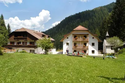 a couple of buildings in a grassy field next to a house at Residence Bad Bergfall in Valdaora